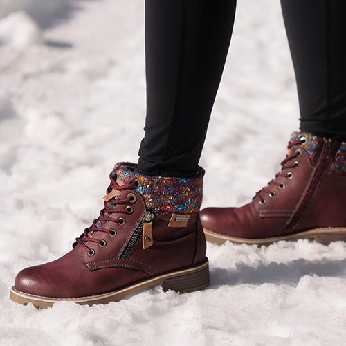 Burgundy lace-up ankle boots with multicoloured fleece cuffs, shown worn in the snow.
