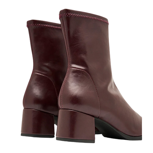 Block heel on a pair of burgundy ankle boots on a white background