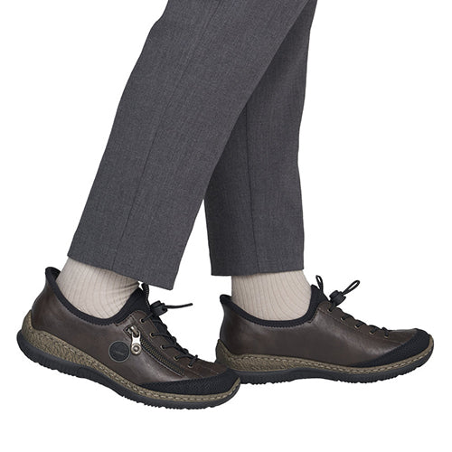 A pair of dark brown leather slip-on shoes with black soles and laces, shown on a person&