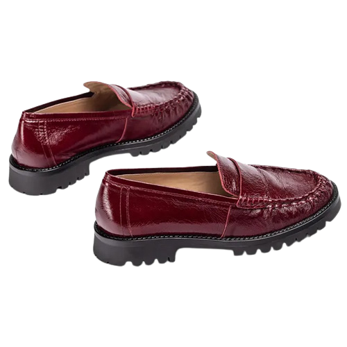 Burgundy patent leather loafers featuring a classic penny loafer design, and chunky black lug soles, shown from the side on a white background.