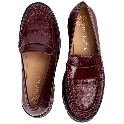 Burgundy patent leather penny loafers with detailed stitched uppers, tan lining and chunky black lug soles, shown from a top-down view on a white background.