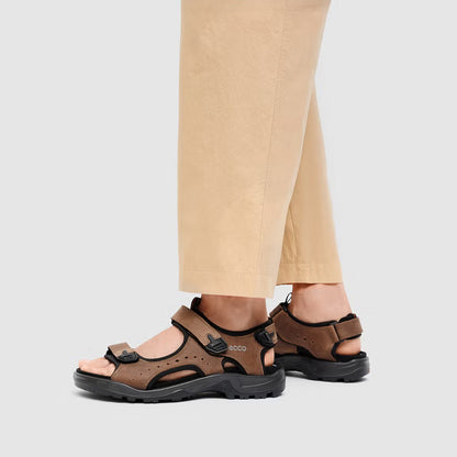 Brown sandals worn with beige pants on a light gray background