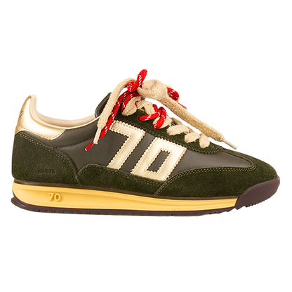 A low-top trainer shown in profile against a white background. The shoe features dark olive green suede panels, a black synthetic overlay, cream-colored &