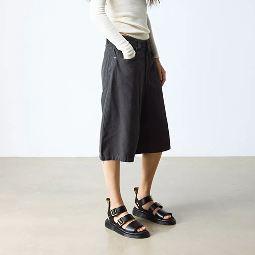 Person wearing black wide-leg pants and black sandals on a plain background