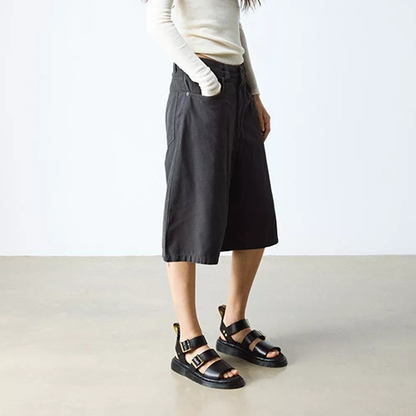 Person wearing black wide-leg pants and black sandals on a plain background