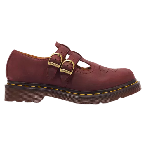 A single Dr. Martens Mary Jane shoe in burgundy leather, featuring two adjustable straps with gold-tone buckles, a perforated toe, and a dark brown sole with yellow stitching.