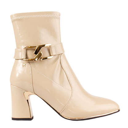 A beige patent leather ankle boot with a block heel and a gold-tone decorative buckle strap around the ankle, shown against a plain white background.