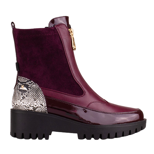 A single ankle boot in deep burgundy, featuring a mix of patent leather and suede textures, a snakeskin-patterned heel accent, a side zipper with a gold pull tab, and a chunky black lug sole, shown against a plain white background.