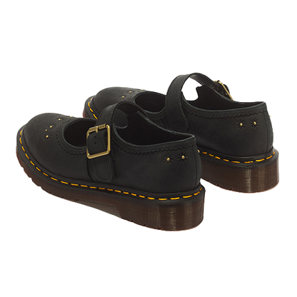 A pair of black leather Mary Jane shoes with gold-tone buckle straps, yellow welt stitching, and brown platform soles, shown from a three-quarters angle on a white background.