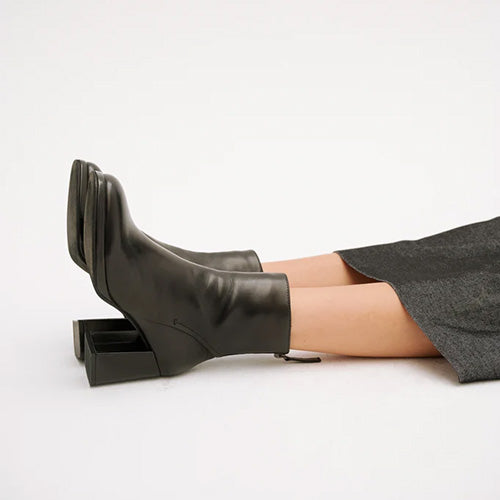 Person wearing a pair of Black Leather Heeled Ankle Boots on a a plain white background 