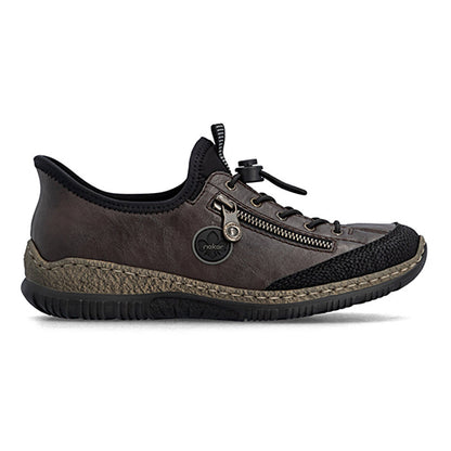 A single low-top slip-on shoe from the brand Rieker, shown in profile against a white background. The shoe features a dark brown textured upper, black mesh panels, a black collar, a silver metal zipper, and a rugged black and brown sole.