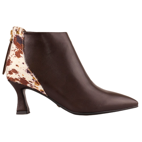 A dark brown leather ankle boot with a pointed toe and a low block heel, featuring a contrasting cow-print pattern panel on the back heel and a gold-tone zipper pull.