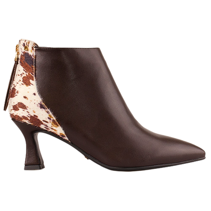A dark brown leather ankle boot with a pointed toe and a low block heel, featuring a contrasting cow-print pattern panel on the back heel and a gold-tone zipper pull.