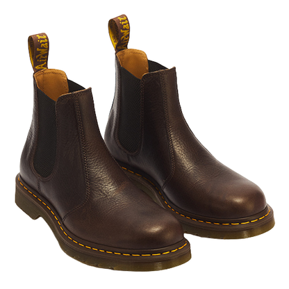 A pair of dark brown leather Chelsea boots with black elastic side panels and signature yellow stitching around the sole, shown on a plain white background.