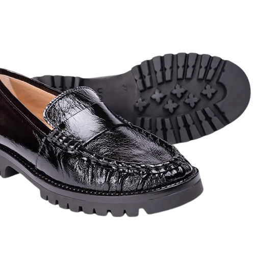 A pair of black patent leather loafers with thick lug soles, with one shoe showing the side profile and the other showing the treaded outsole.