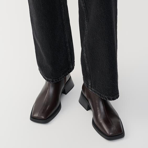 Brown leather boots worn with black jeans on a white background