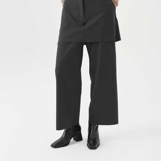 Person wearing a black outfit with wide-leg pants on a white background