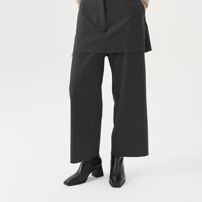 Person wearing a black outfit with wide-leg pants on a white background