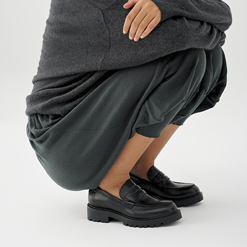 Person wearing gray trousers and black shoes on a white background