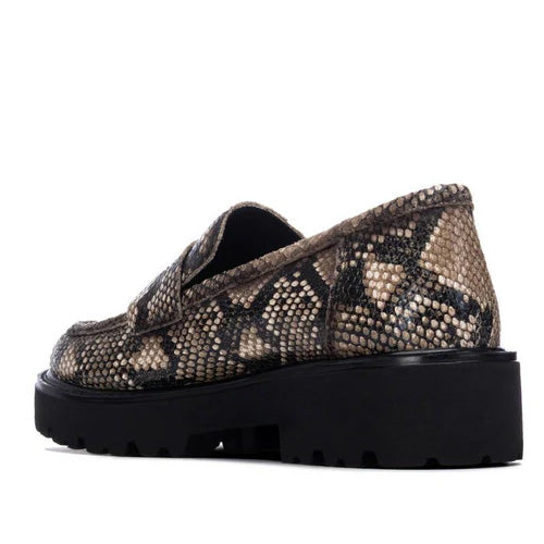 A single slip-on loafer with a black and beige snakeskin pattern, featuring a chunky black platform sole, shown from a side profile on a white background.