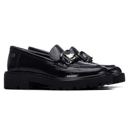 A pair of black patent leather slip-on loafers with chunky lug soles and a decorative silver-tone buckle detail across the vamp, shown against a plain white background.