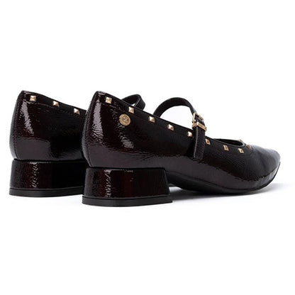 A pair of burgundy patent leather Mary Jane shoes with gold-tone studs and buckles, shown from a side profile on a white background.