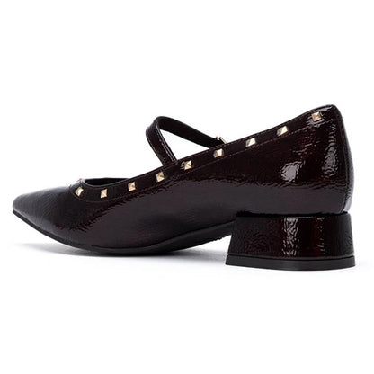 A burgundy patent leather Mary Jane shoe with gold pyramid studs, shown from a side profile view on a white background.