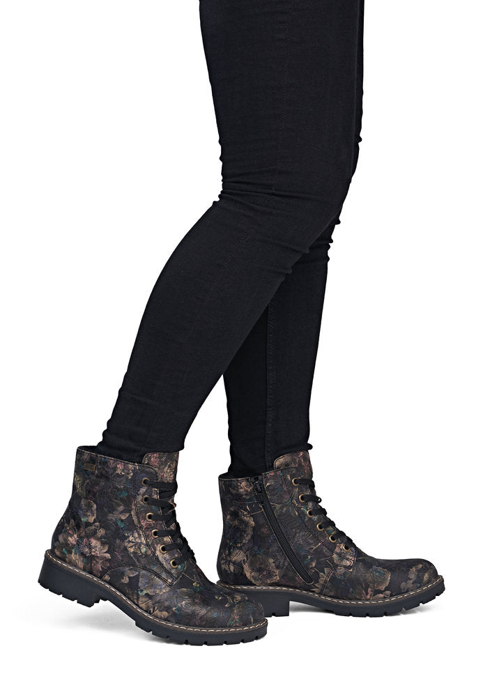 Black patterned boots worn with black leggings on a white background