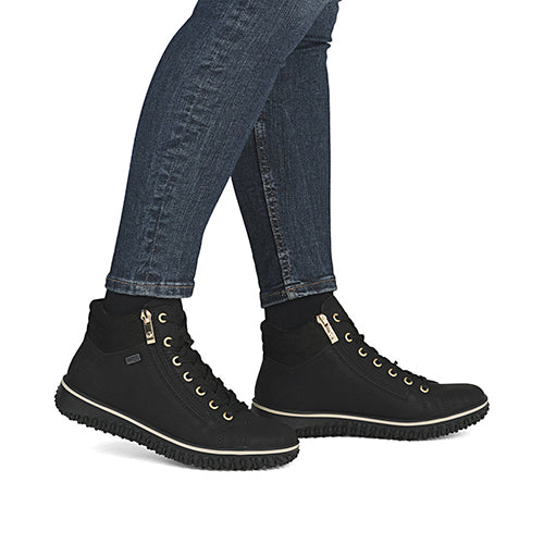Black high-top sneakers with gold zippers worn with blue jeans on a white background